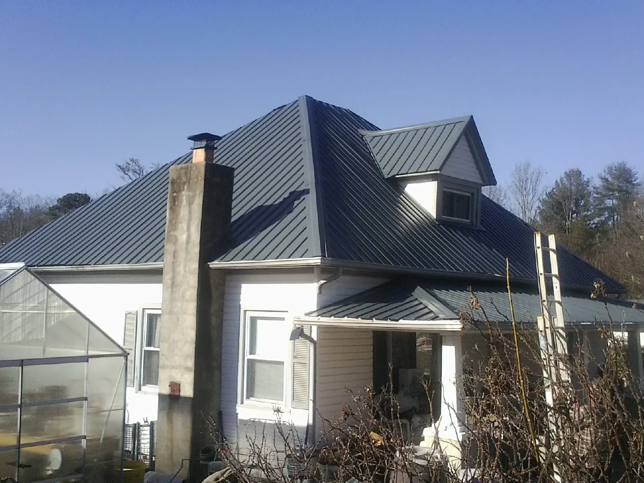 Dark blue standing seam metal roof on a white farmhouse with dormer — Slate & Tile Roof Repair by Roofing Brothers in Saxonburg
