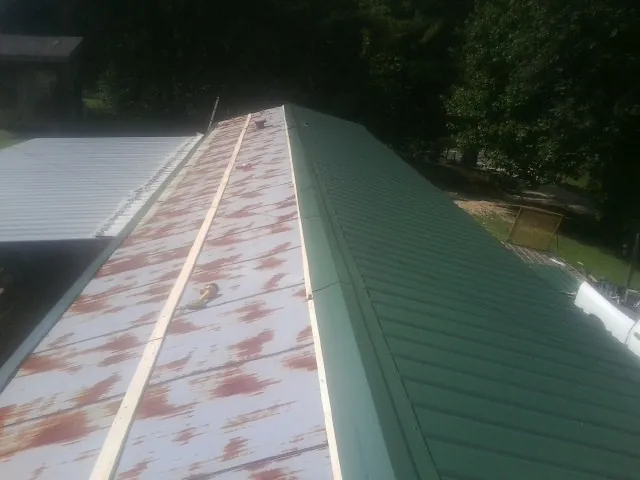 Old rusted panels beside newly installed green metal roofing — Wind Damage Roof Repair by Roofing Brothers in Saxonburg