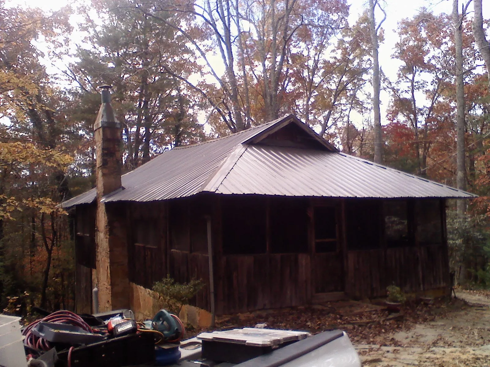 Brown metal hip roof on an old cabin with a stone chimney in Saxonburg
