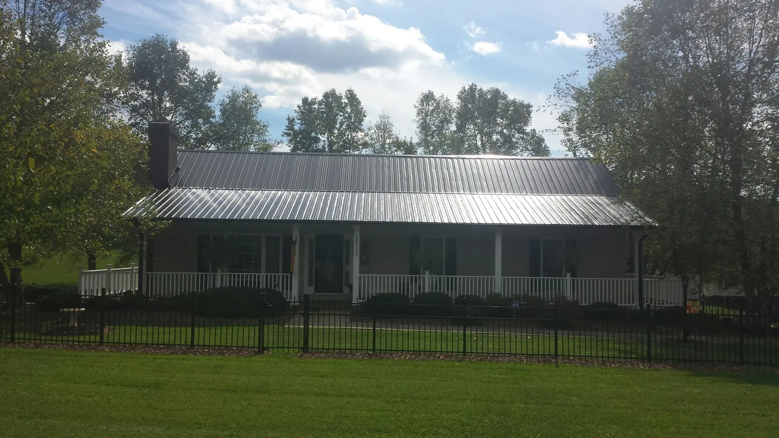 Gray metal roof on a brick ranch with a full width front porch — Gutter Guard Installation work by our crew in Saxonburg