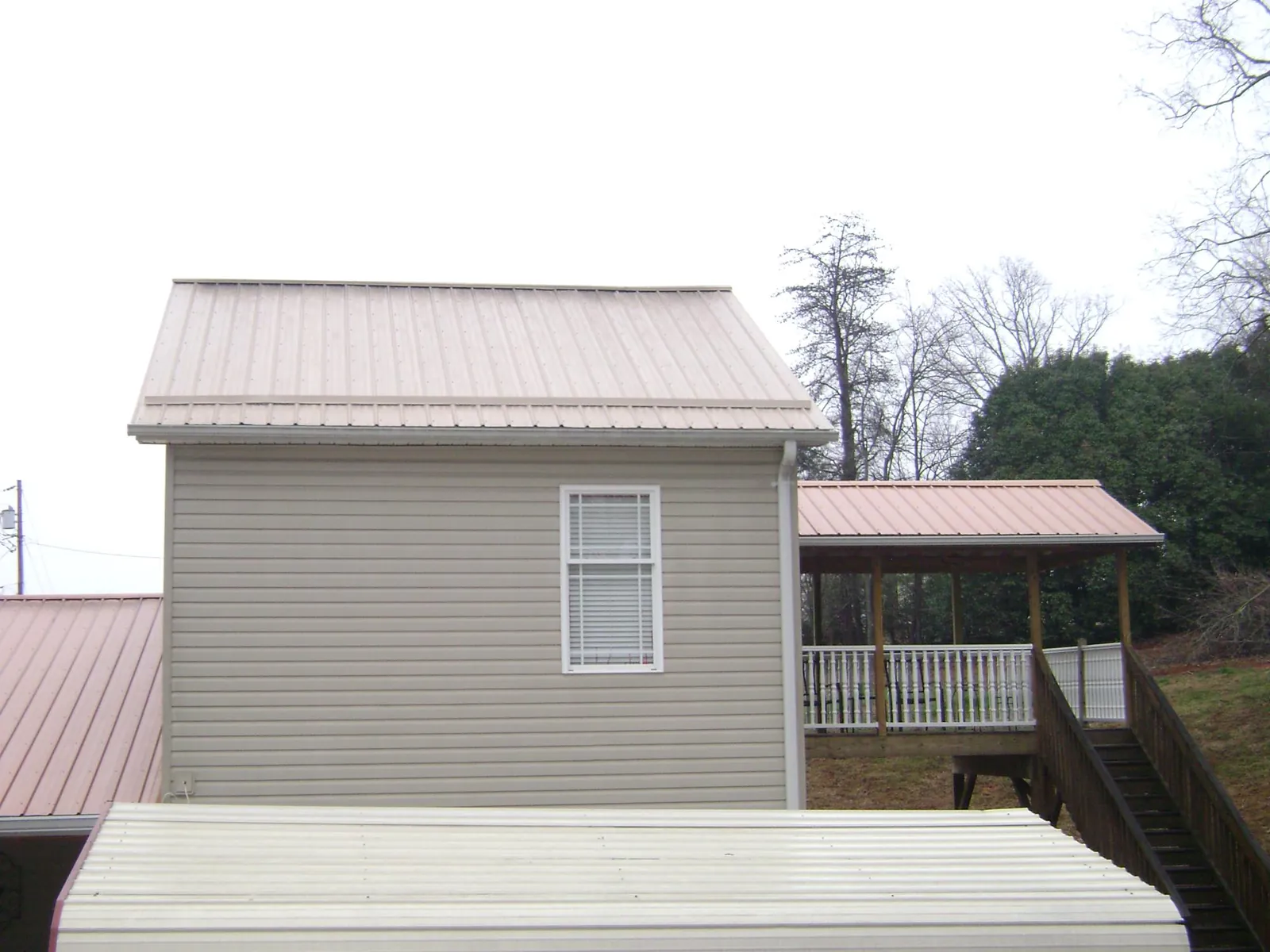 Tan metal roofs on a two story addition and attached porch, from a Roof Replacement job in Saxonburg