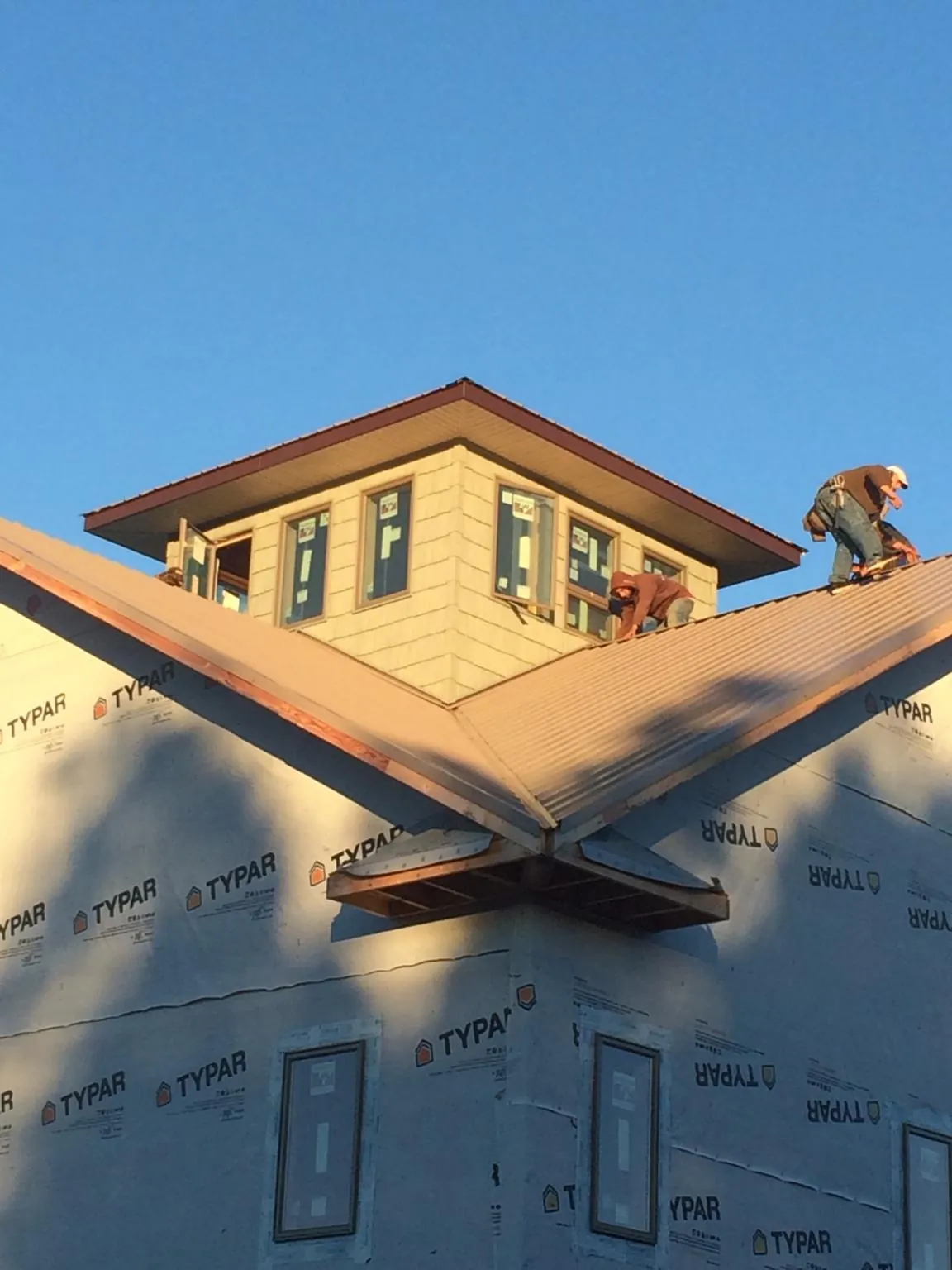 Roofers working around a rooftop cupola on a new metal roof at sunset — Roof Waterproofing in Saxonburg by Roofing Brothers